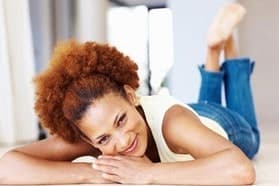 A smiling woman with curly hair lying on the floor
