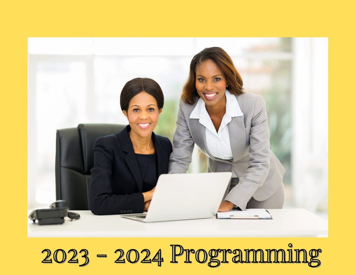 2023 - 2024 Programming. Two smiling Black businesswomen at an office desk with a laptop.